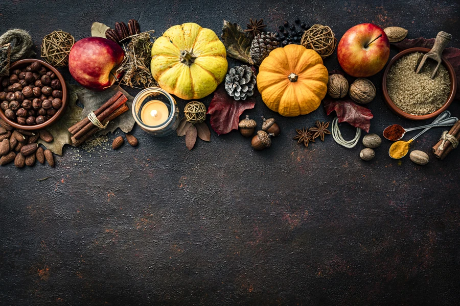 A scented candle with other Thanksgiving decorations on a table