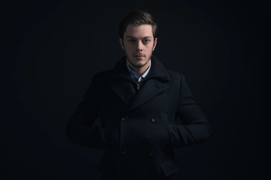 A serious-looking man in a black peacoat