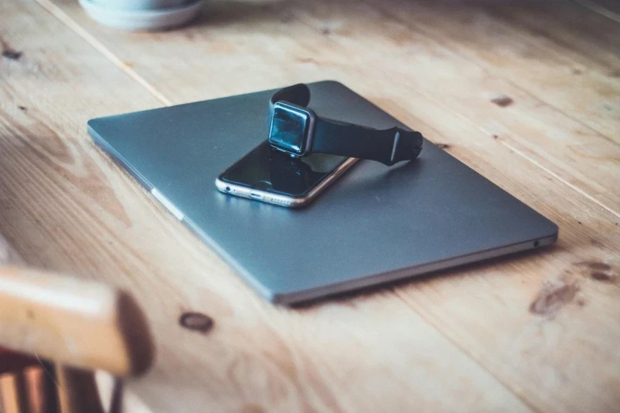 A smart watch and a phone on a laptop