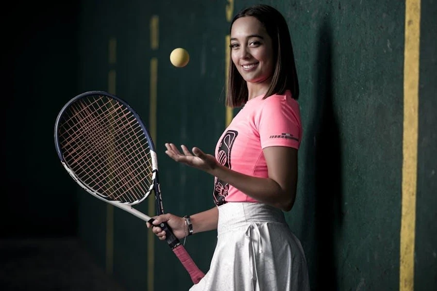 A smiling woman wearing a tennis outfit with tennis balls