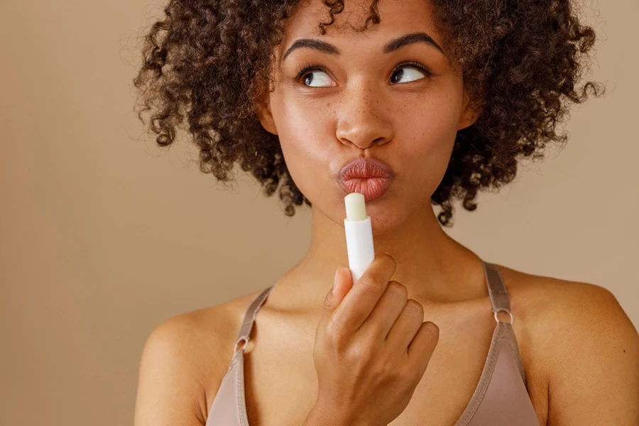 A stylish woman posing with a lip product