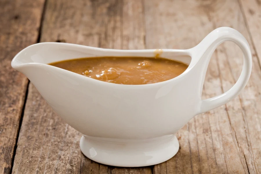 A white ceramic gravy boat filled with sauce