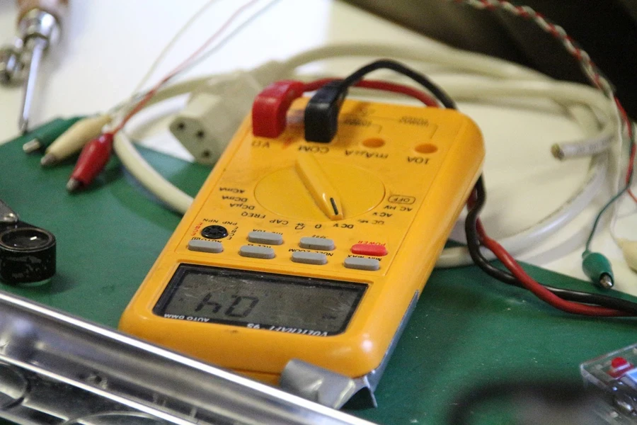 A yellow digital multimeter with black and red wires