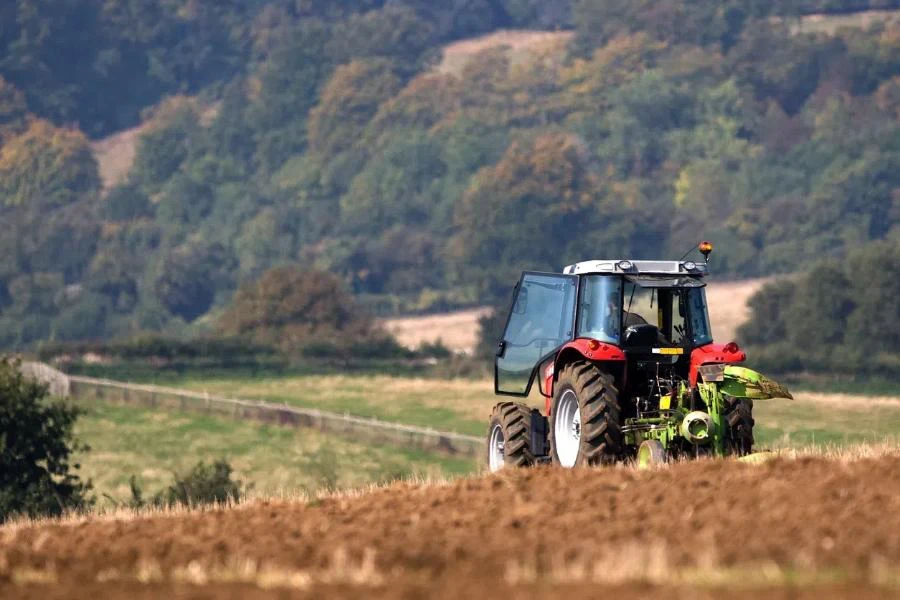 Agricultural tractor ploughing a field in a rolling English landscape