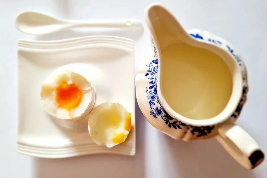 An egg beside a ceramic gravy boat