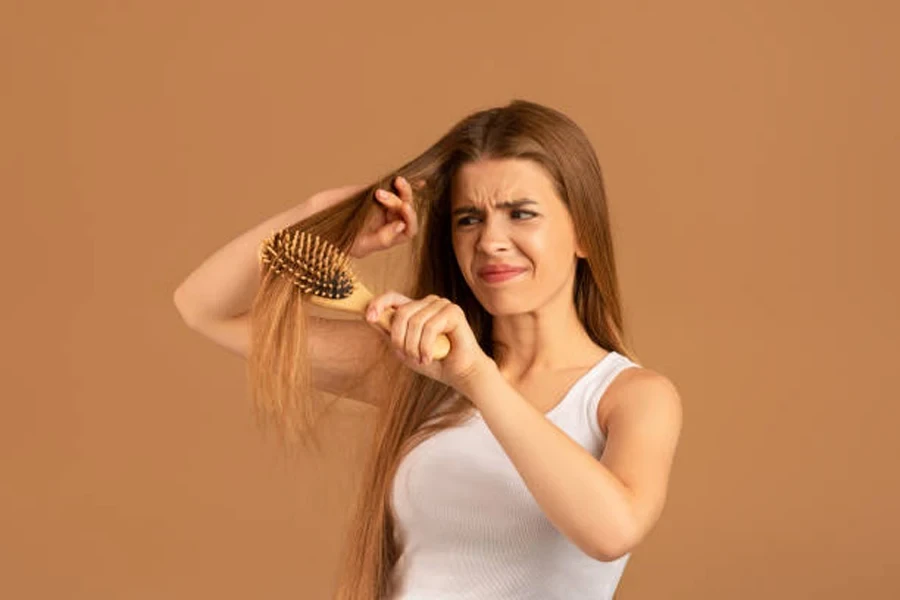 Annoyed Young Woman Having Problem Brushing Her Long Hair