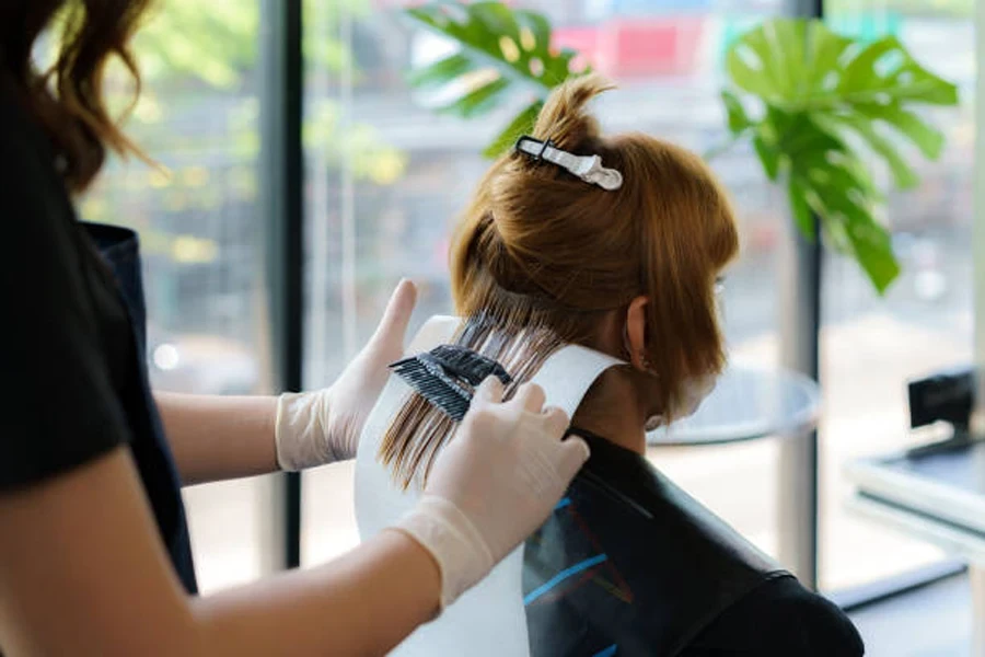 Attractive Brunette Hairdresser Thoroughly Dyeing Hair of Female Client