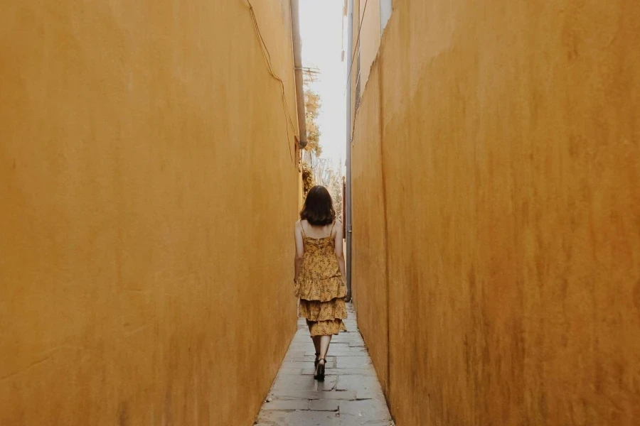 Back View of a Woman Walking in a Narrow Alley