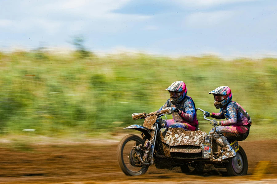 Blurry Photo of Sidecarcross Bikers Racing on Mud Track