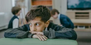 Boy in Black and White Long Sleeve Shirt Sitting on Green Leather Couch