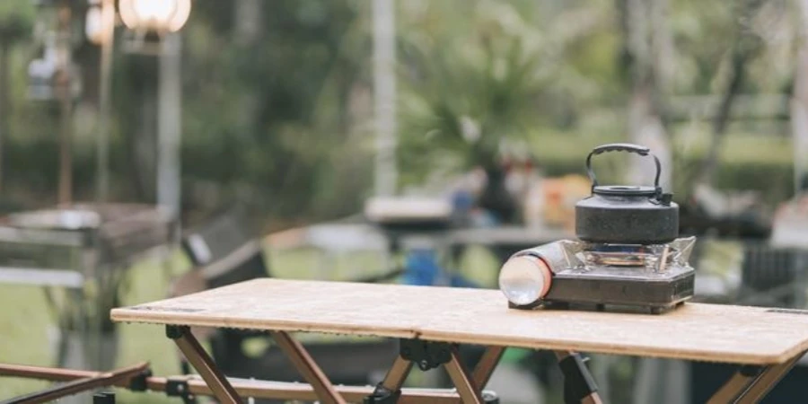 Camping stove hot kettle boiling on picnic table in the morning