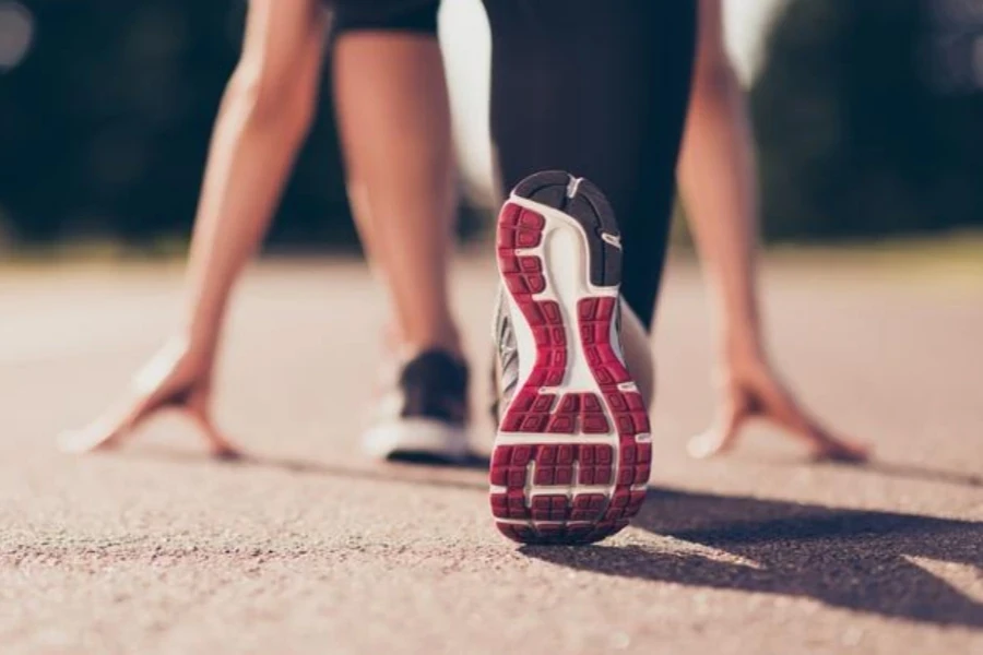 Close up cropped low angle photo of female athlete's shoes on the starting line of a stadium track, preparing to run