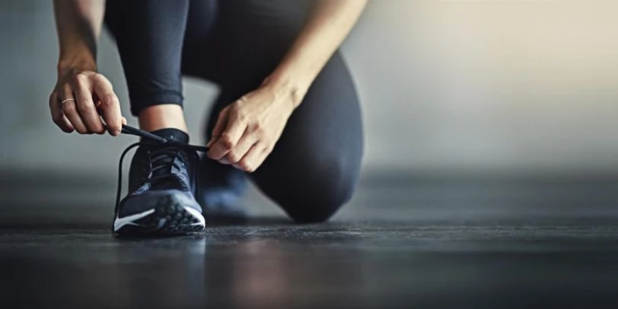 Cropped shot of a woman tying her shoelaces before working out