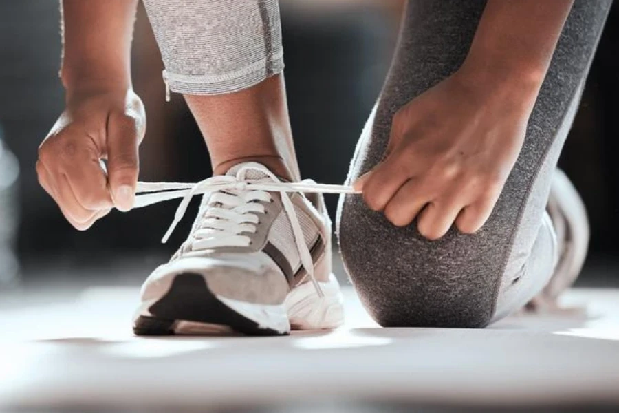 Cropped shot of unrecognizable woman tying shoelaces while exercising at gym