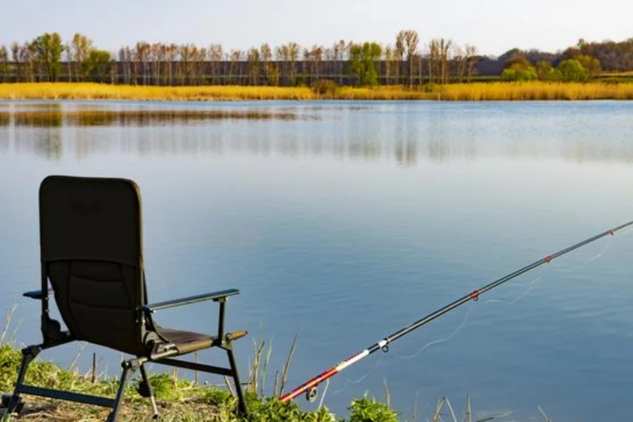 Empty chair and fishing rods on the lake shore in the morning