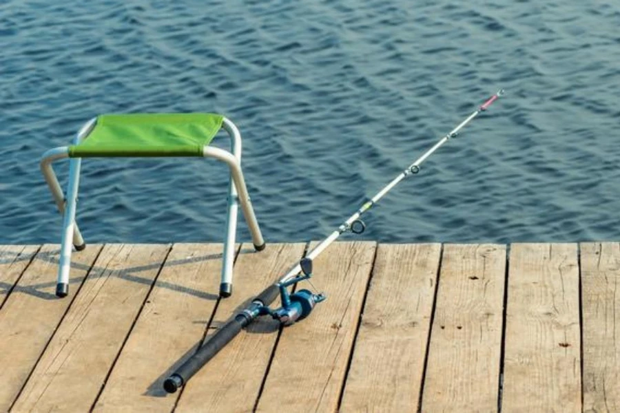 Empty chairs and fishing rods on a wooden pier near the lake