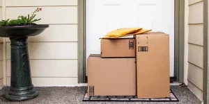 Puerta de entrada de una casa con una pila de cajas de entrega de pedidos en línea y comercio electrónico