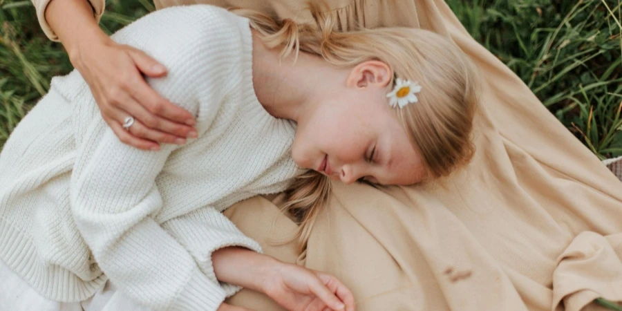 Girl in White Sweater Lying on Brown Textile