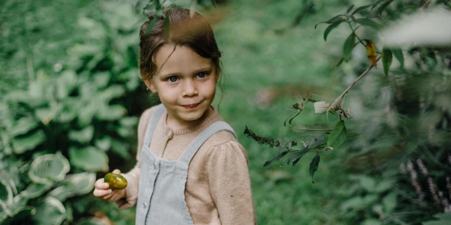 Girl in white long sleeve shirt holding green fruits