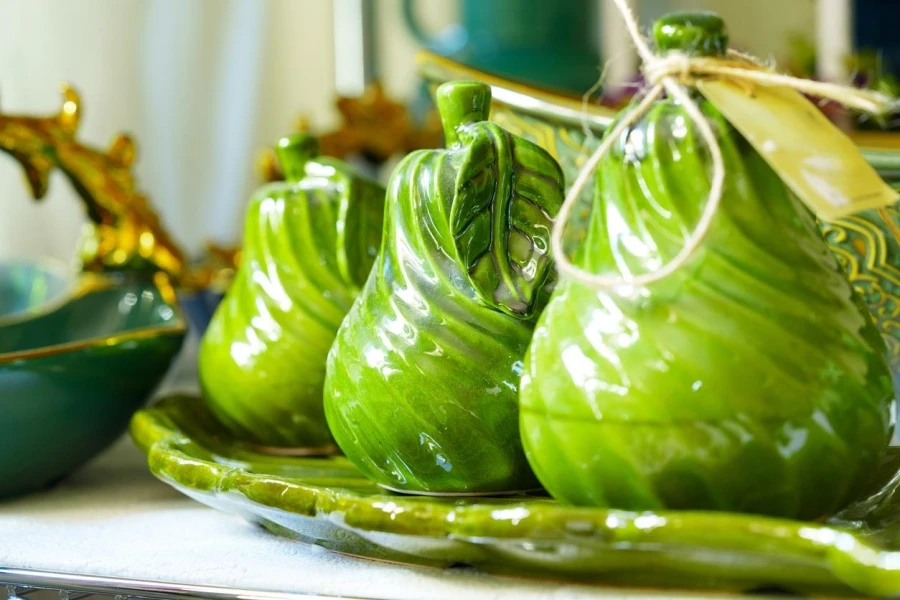 Green ceramic pear-shaped container on plate with rustic kitchen decor