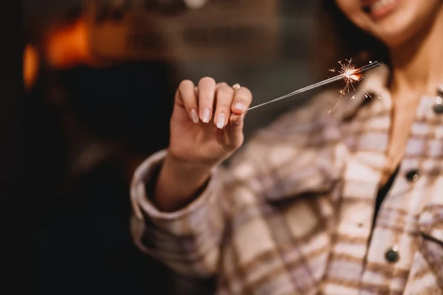 Hand holding sparkler with nude French nail design