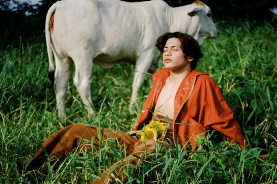 Man In Orange Top Wear Sitting On Grassland