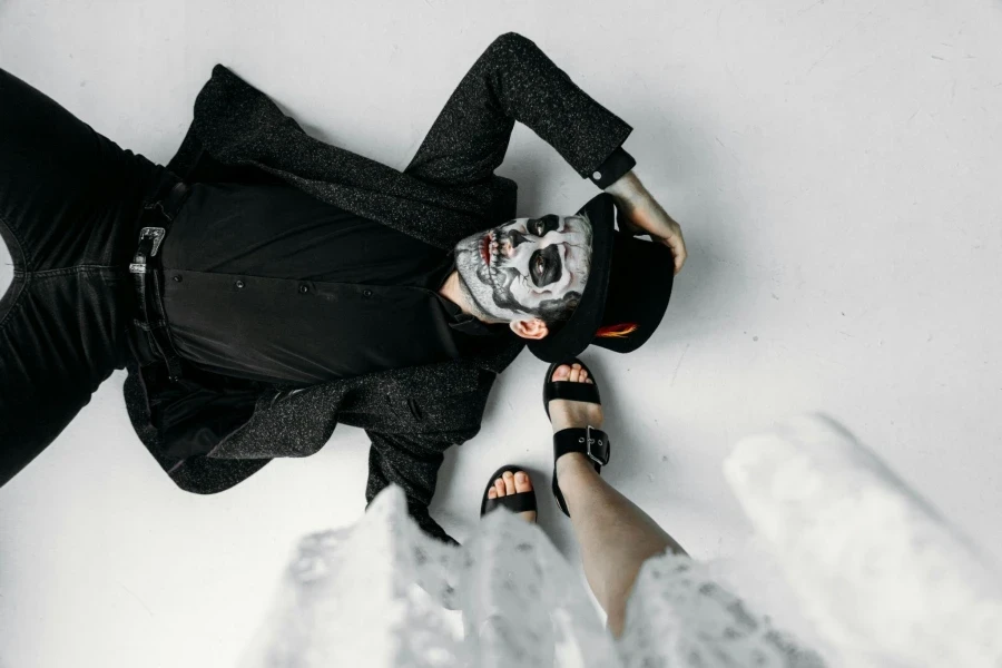 Man Lying On Floor With Face Paint And Woman Standing Beside Him