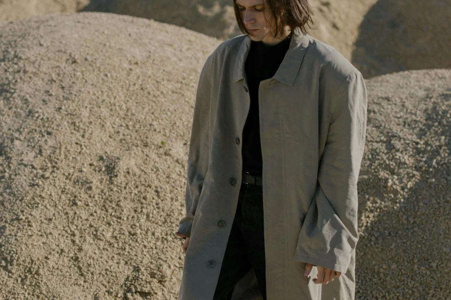 Man Wearing Beige Trench Coat and Black Shirt Standing Near Sand Dunes