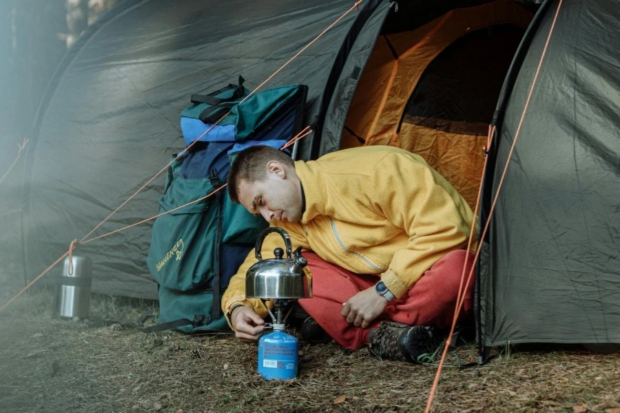 Man boiling water next to tent