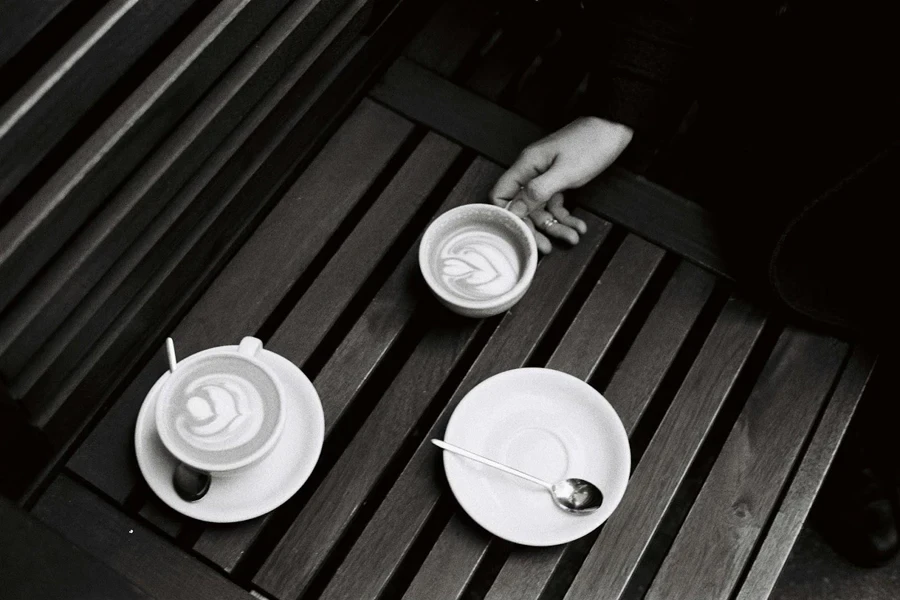 Man grabbing a cup of coffee with teaspoons on saucers