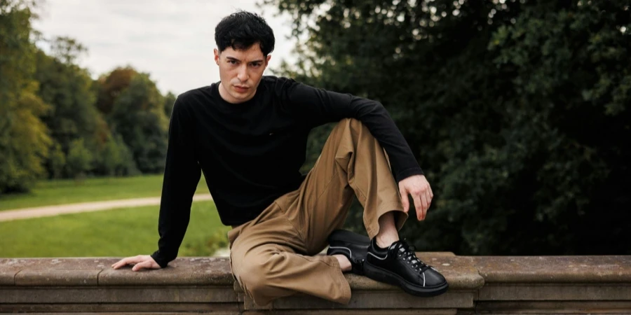 Man in Black Blouse Sitting on Wall