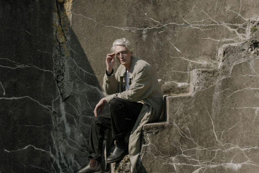 Man in Brown Suit Sitting on Brown Wooden Seat