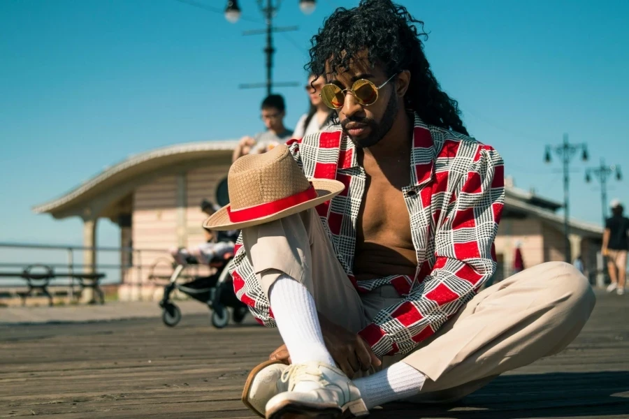 Man in Red and Gray Dress Shirt Sitting on Ground