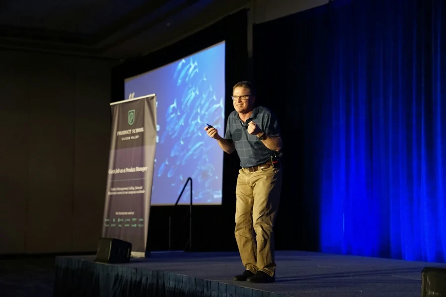 Man speaking on stage for a presentation during a conference