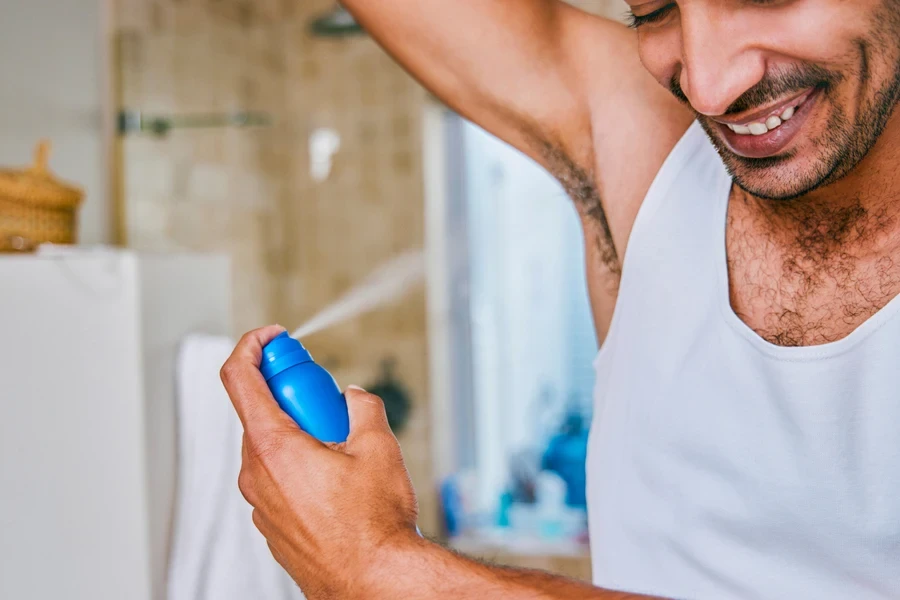 Man spraying deodorant on his armpit