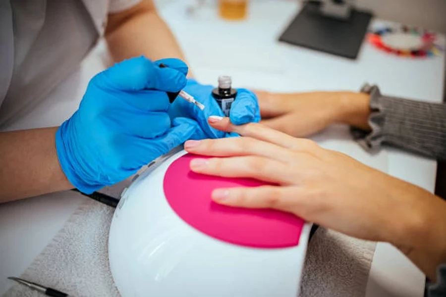 Nail artist putting coating on customer’s nails in salon