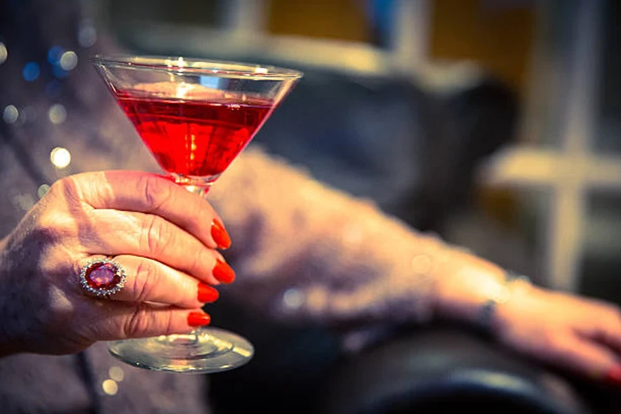 Older woman holding glass of red cocktail at party