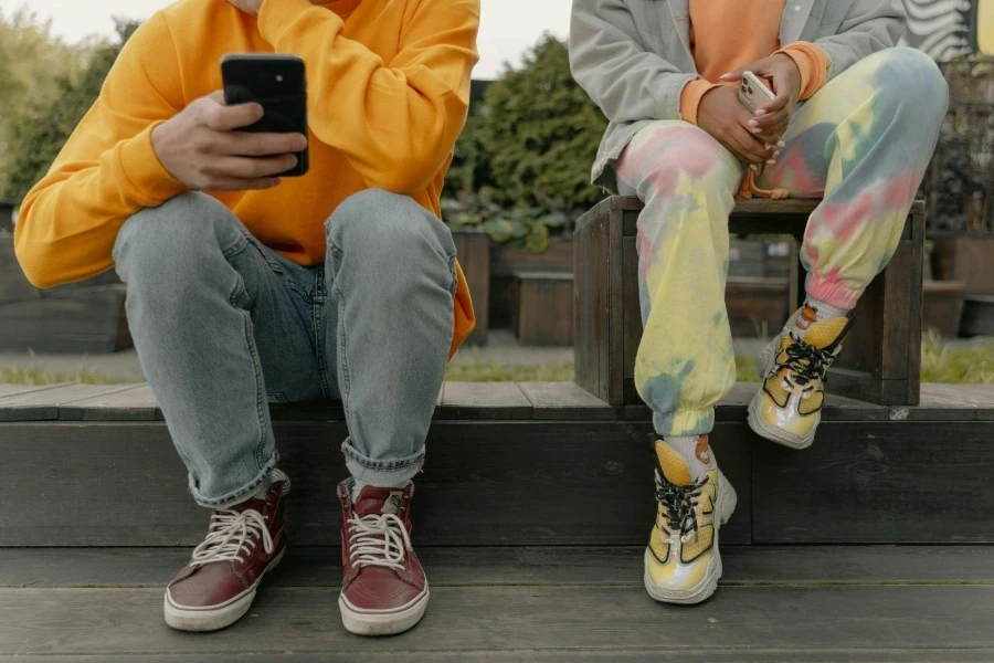 People Sitting on a Wooden Platform Holding Smartphones