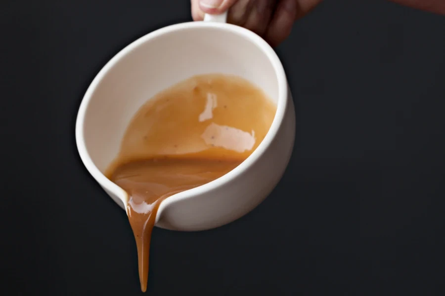 Person pouring sauce from a gravy Bowl