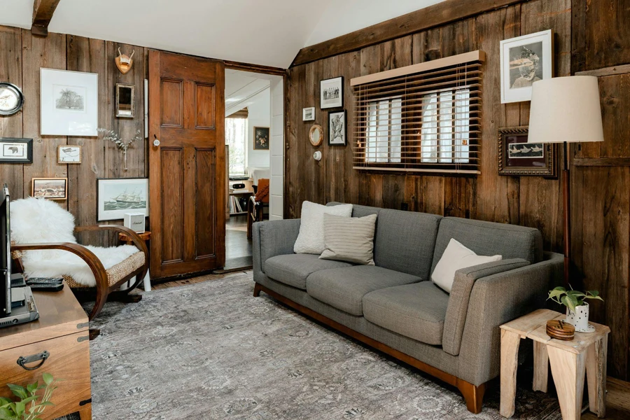 Rustic living room interior with wood paneling and gray couch