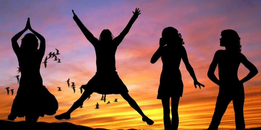 Silhouette of 4 Women With the Background of Birds Flying Under Yellow and Grey Sky