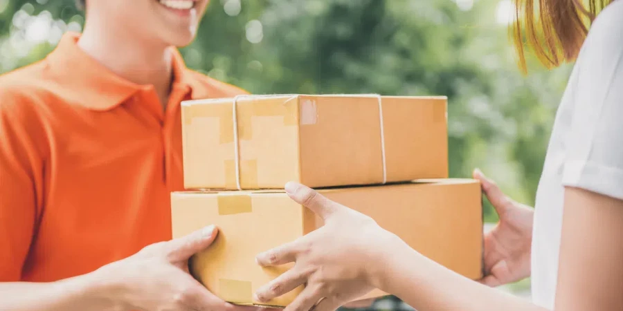 Smiling delivery man in orange uniform delivering parcel box to a woman customer