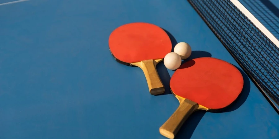 Table tennis ping pong paddle and white ball on blue board