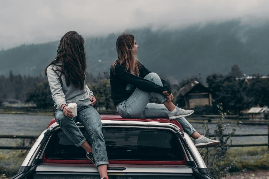 Two Women Sitting on Vehicle Roofs