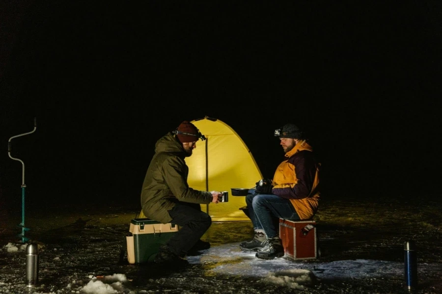 Two men drinking water beside the camping tent