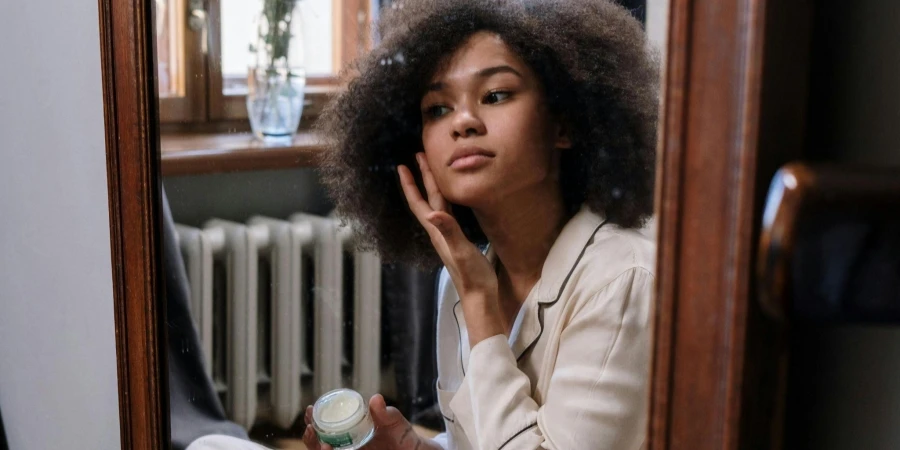 Woman Applying Skin Care Products in the Mirror