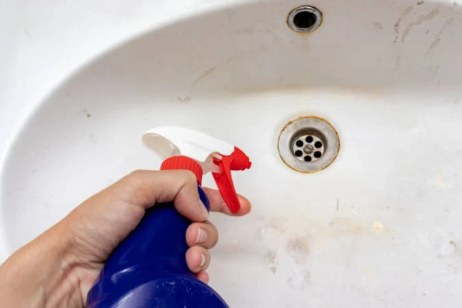 Woman Holding a Sprayer Cleaning Agent for Wasing Old Dirty Washbasin with Rust Stains, Limescale and Soap Stains