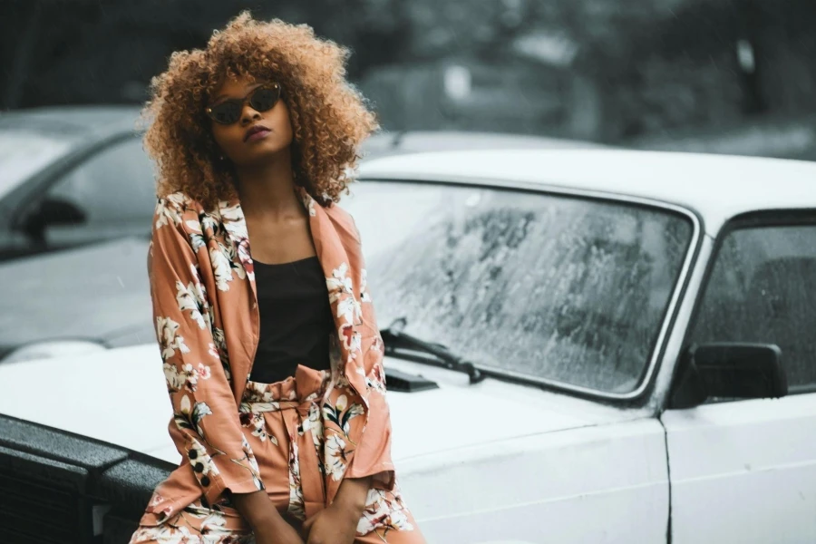 Woman Wearing Brown Floral Print Coat and Pants Sitting on Car