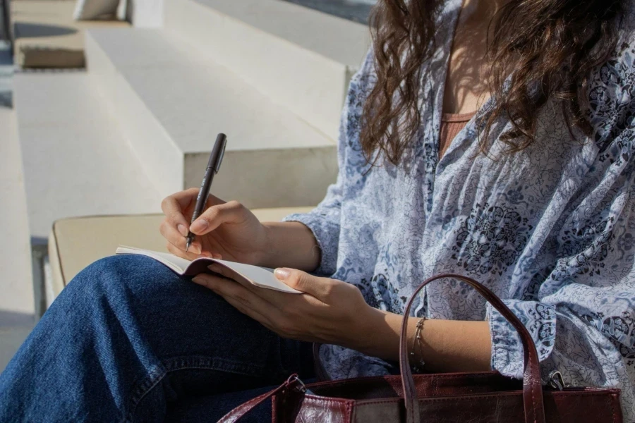 Woman Writing in Notebook on Outdoor Steps