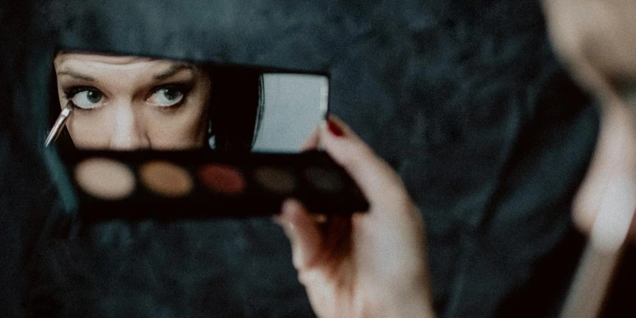 Woman applying eyeshadow in a mirror